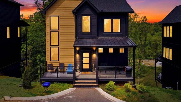 A two-story house with a porch, a deck, and a garage.