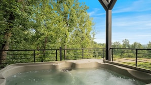 A hot tub with a view of a forested area.