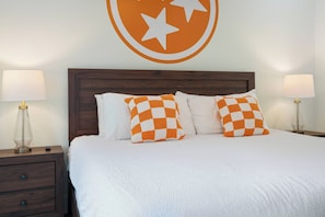 A neatly made bed with white and orange checkered pillows, flanked by two bedside lamps on wooden nightstands.