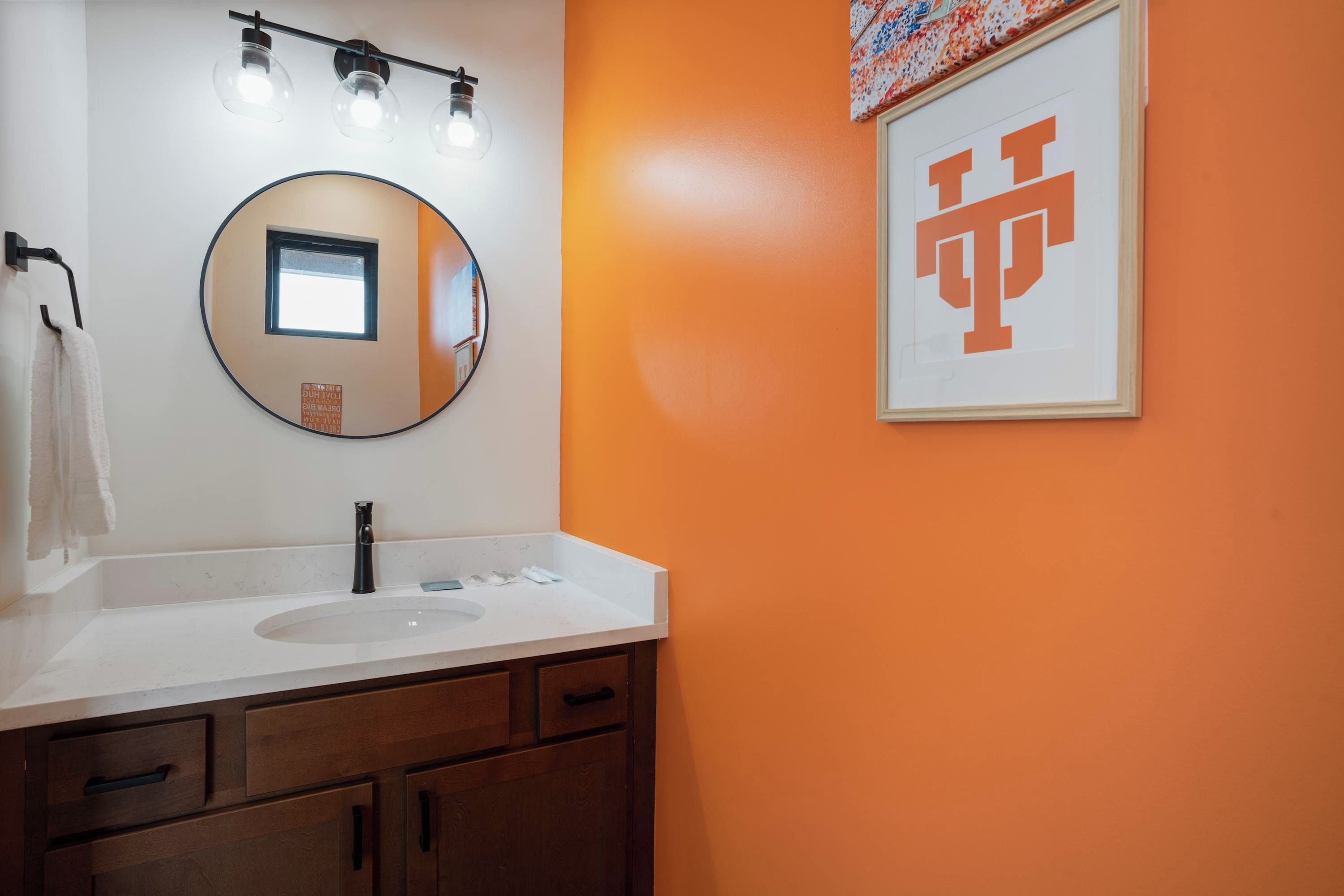 A bathroom with a white sink, a round mirror, and a towel rack.