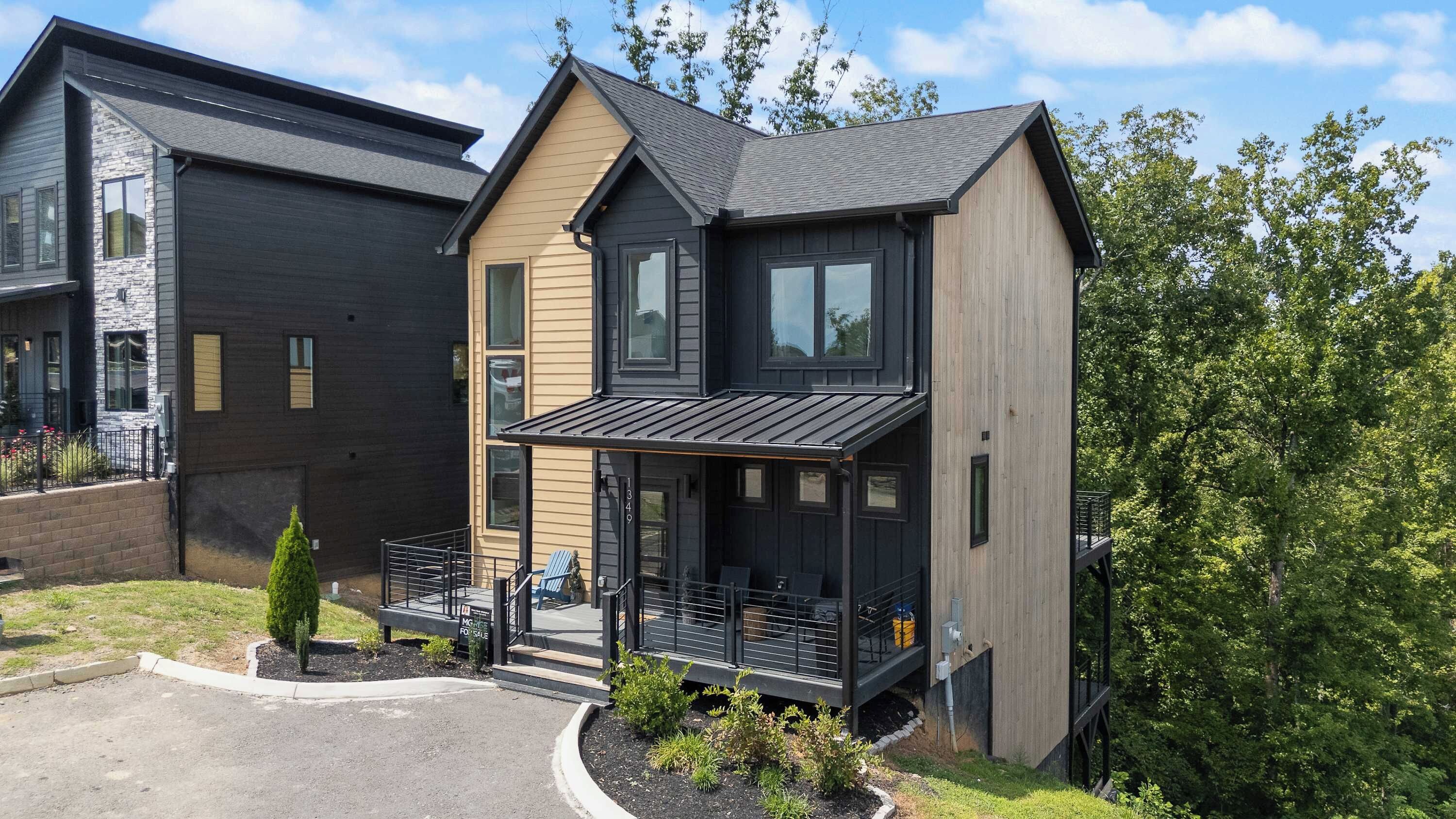 Ein modernes, zweistöckiges Haus mit einer Veranda und einer kleinen Terrasse.