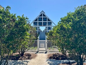 A building with a triangular roof and a central staircase leading to a door with a plaque. - Renovated Beachside Seaside Home; Porches, Outdoor Dining & Serene Gulf Views (Santa Rosa Beach)