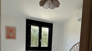 Ein Schlafzimmer mit Bett, Fenster, Tür und einer Hängelampe.