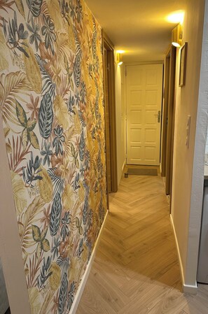 A hallway with a floral wallpaper, wooden flooring, and a door at the end. - 3-bedroom apartment with panoramic sea view (Grosseto-Prugna)