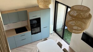 Eine moderne Küche mit hellblauen Schränken, einem weißen Esstisch und einem großen Fenster.