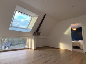 A room with a sloped ceiling, skylight, wooden flooring, and a bed with a dark headboard. - Magnificent renovated farmhouse in peaceful countryside setting (Rives-du-Couesnon)
