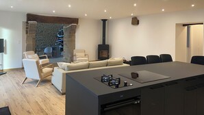 A modern kitchen with a central island, a stone fireplace, and a cozy seating area with a Christmas tree. - Magnificent renovated farmhouse in peaceful countryside setting (Rives-du-Couesnon)