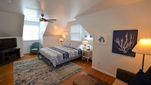 A bedroom with a bed, a TV, a ceiling fan, a window, a lamp, and a framed picture on the wall. - Quaint Pet Friendly Home In South Rehoboth! (Rehoboth Beach)