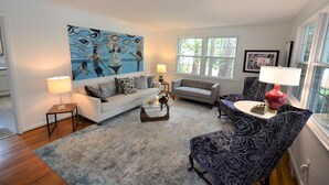 A living room with a sofa, armchair, coffee table, and artwork on the wall. - Quaint Pet Friendly Home In South Rehoboth! (Rehoboth Beach)