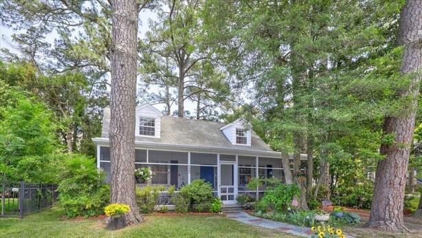 A house with a porch, surrounded by trees and a well-maintained lawn. - Quaint Pet Friendly Home In South Rehoboth! (Rehoboth Beach)