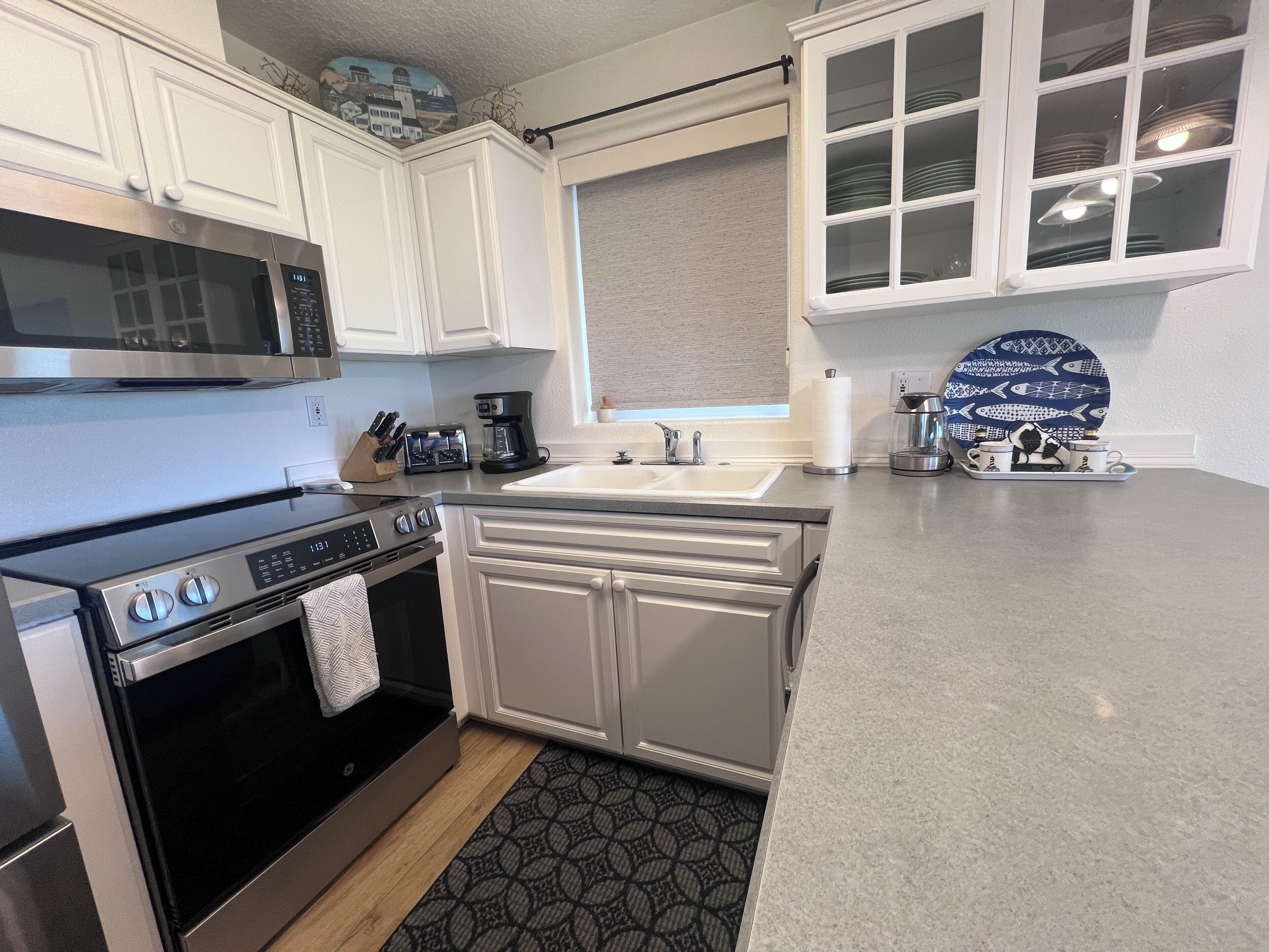 A kitchen with white cabinets, a stainless steel microwave, a coffee maker, and a sink.