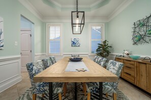A dining area with a wooden table, patterned chairs, and a hanging light fixture. - Beautiful Single Family Home With Tons Of Amenities! (Rehoboth Beach)