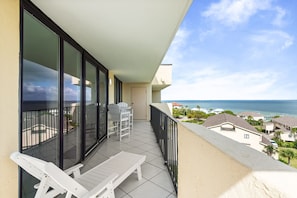 A balcony with white chairs, a table, and a view of the ocean. - 🏖️ Santa Rosa Dunes 1061: Steps to the Gulf, Pool + Stunning Sound Views! (Pensacola Beach)