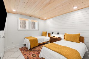 A bedroom with two beds, a wooden ceiling, a window with blinds, a nightstand, and a patterned rug. - 🏖️ Santa Rosa Dunes 1061: Steps to the Gulf, Pool + Stunning Sound Views! (Pensacola Beach)