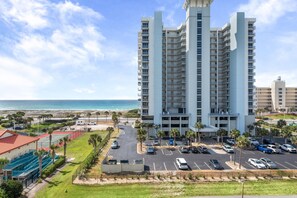 Un hotel de gran altura con varios balcones, un estacionamiento y vistas a la playa.