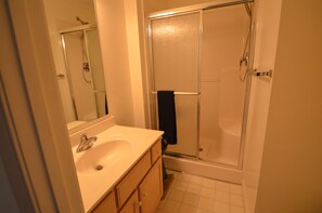 A bathroom with a sink, mirror, and glass-enclosed shower. - Townhouse Close to Route One and Downtown Rehoboth Beach! (Rehoboth Beach)