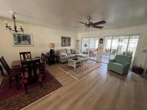 Ein geräumiges Wohnzimmer mit Essbereich, Deckenventilator und Blick durch Glastüren.