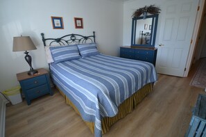A bedroom with a bed, nightstand, dresser, and a mirror. - Townhouse Close to Route One and Downtown Rehoboth Beach! (Rehoboth Beach)