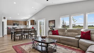 A spacious living area with a glass coffee table, a beige sofa, and a dining area with wooden furniture.
