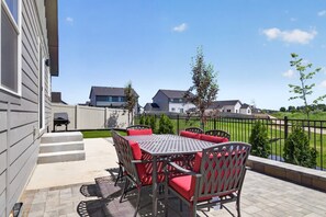 Eine Außenpatio mit Tisch und Stühlen, einem Grill und Blick auf Häuser im Hintergrund.