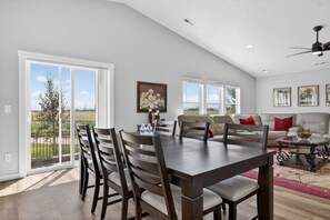 A dining area with a table and chairs, a sofa, and a ceiling fan.