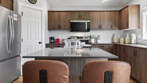 A modern kitchen with wooden cabinets, stainless steel appliances, and a central island. - Sweet Esmeralda-FirePit, BBQ, Pets OK, Fenced Yard (Nampa)