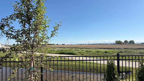 A fenced outdoor area with a tree, a body of water, and a clear sky. - Sweet Esmeralda-FirePit, BBQ, Pets OK, Fenced Yard (Nampa)
