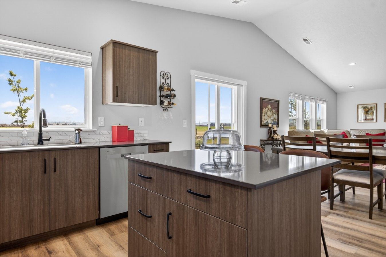 A modern kitchen with a large island, wooden cabinets, and a view of the outdoors.