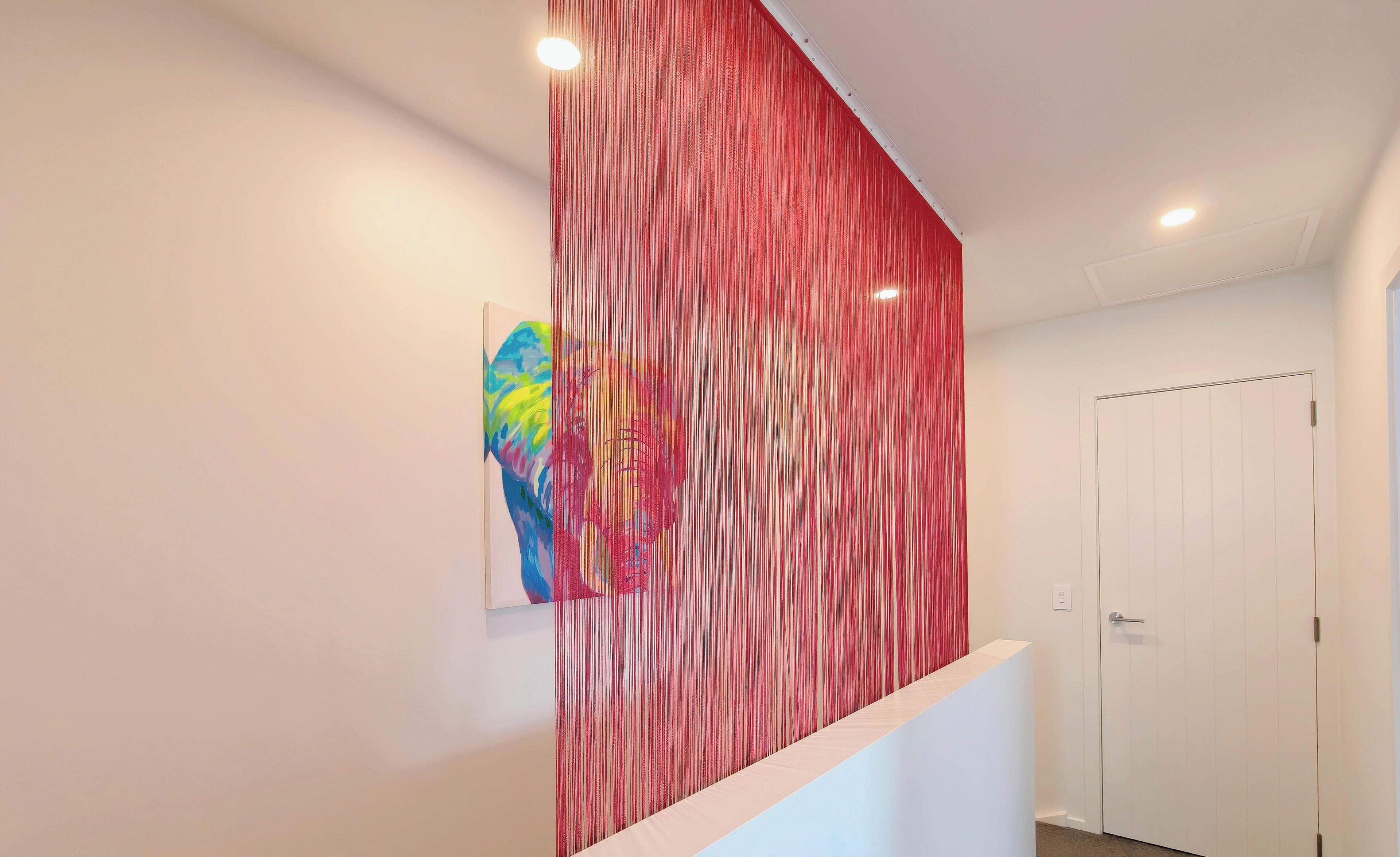 A hallway with a red textured wall, a white door, and a small artwork on the wall.