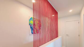 A hallway with a red textured wall, a white door, and a small artwork on the wall.