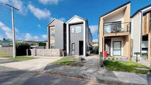 A modern residential area with two-story houses, a clear sky, and a street with a sidewalk. - Relaxing Modern Stay in Upper Hutt Central (Upper Hutt)