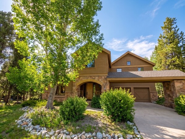 A two-story house with a stone facade, a garage, and a landscaped front yard with a stone pathway. - Riverside 5BR Home: Scenic Serenity & Trail Bliss (Keystone)