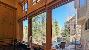 A kitchen with a large window, a sink, and a dining area visible outside. - Last Lift Lodge |  River Views, Grill, & Garage (Keystone)