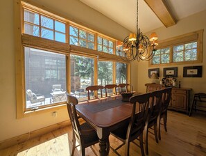 A dining area with a wooden table and chairs, large windows with blinds, and a chandelier. - West Keystone Retreat | 2 King Suites + Fireplace (Keystone)