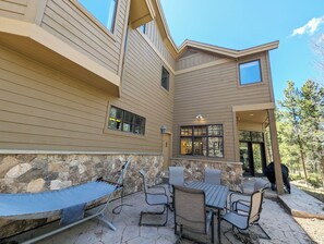 A house with a stone wall, a hammock, and a patio with chairs and a table. - Riverside 5BR Home: Scenic Serenity & Trail Bliss (Keystone)