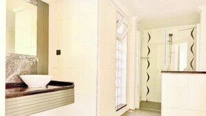 A bathroom with a marble sink, a large mirror, and a shower with a glass door.