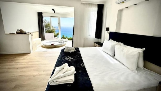 A hotel room with a large bed, a view of the sea, and a balcony.