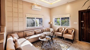 A modern living room with a sectional sofa, two armchairs, a coffee table, and a ceiling fan. - ELIVAAS Shourya Villa 3-BHK Villa (Udaipur)