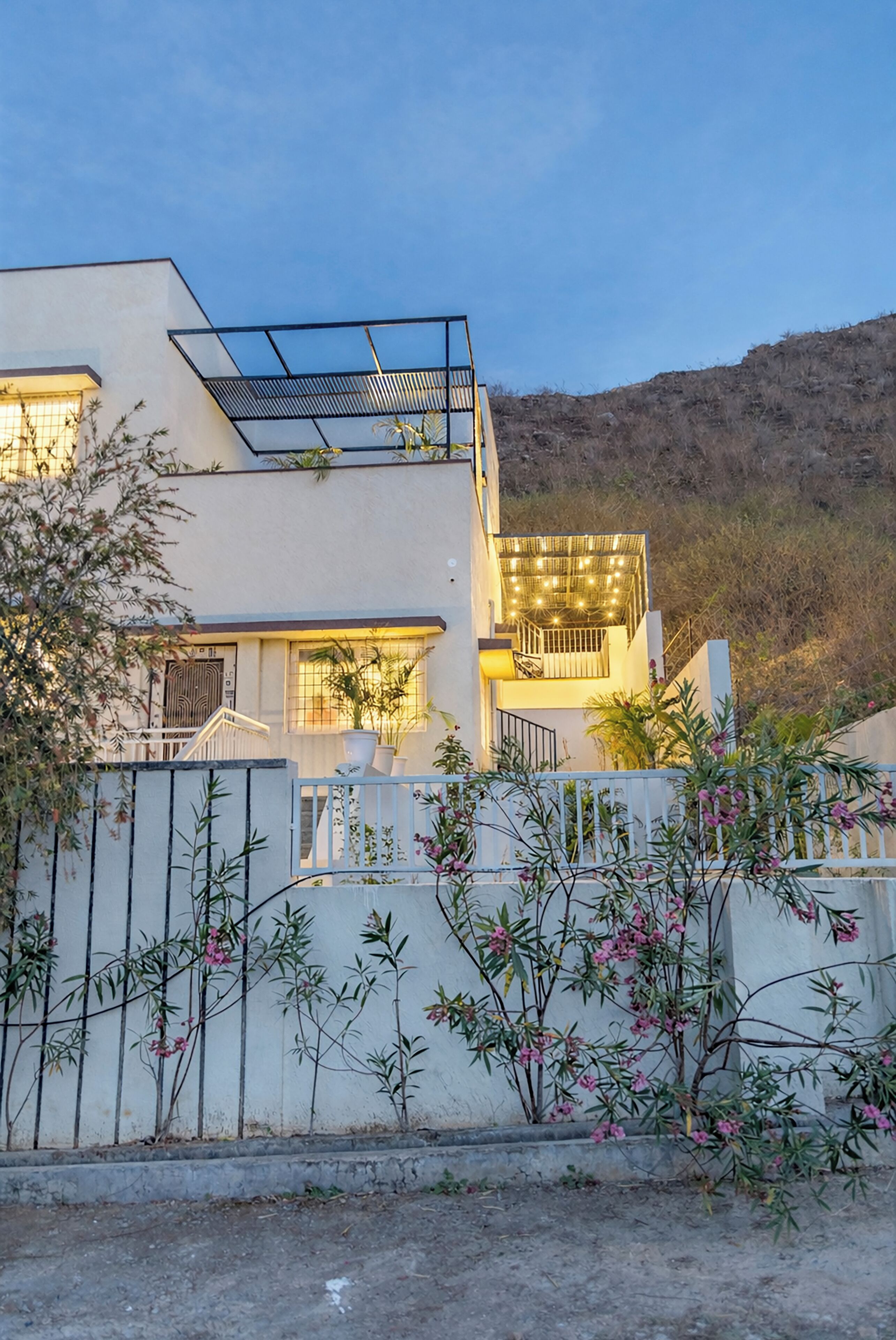 Una casa moderna de dos pisos con un balcón, una escalera y vistas a una colina.