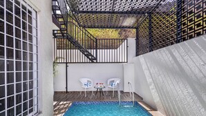 A swimming pool with a tiled edge, a metal ladder, and two white chairs with cushions. - ELIVAAS Shourya Villa 3-BHK Villa (Udaipur)