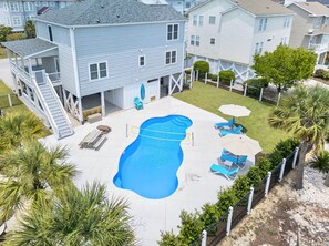 Propiedad residencial con piscina, mobiliario de exterior y patio cercado.