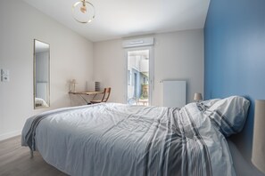 Une chambre à coucher comprenant un lit, un bureau, une chaise, un miroir et donnant sur un escalier.