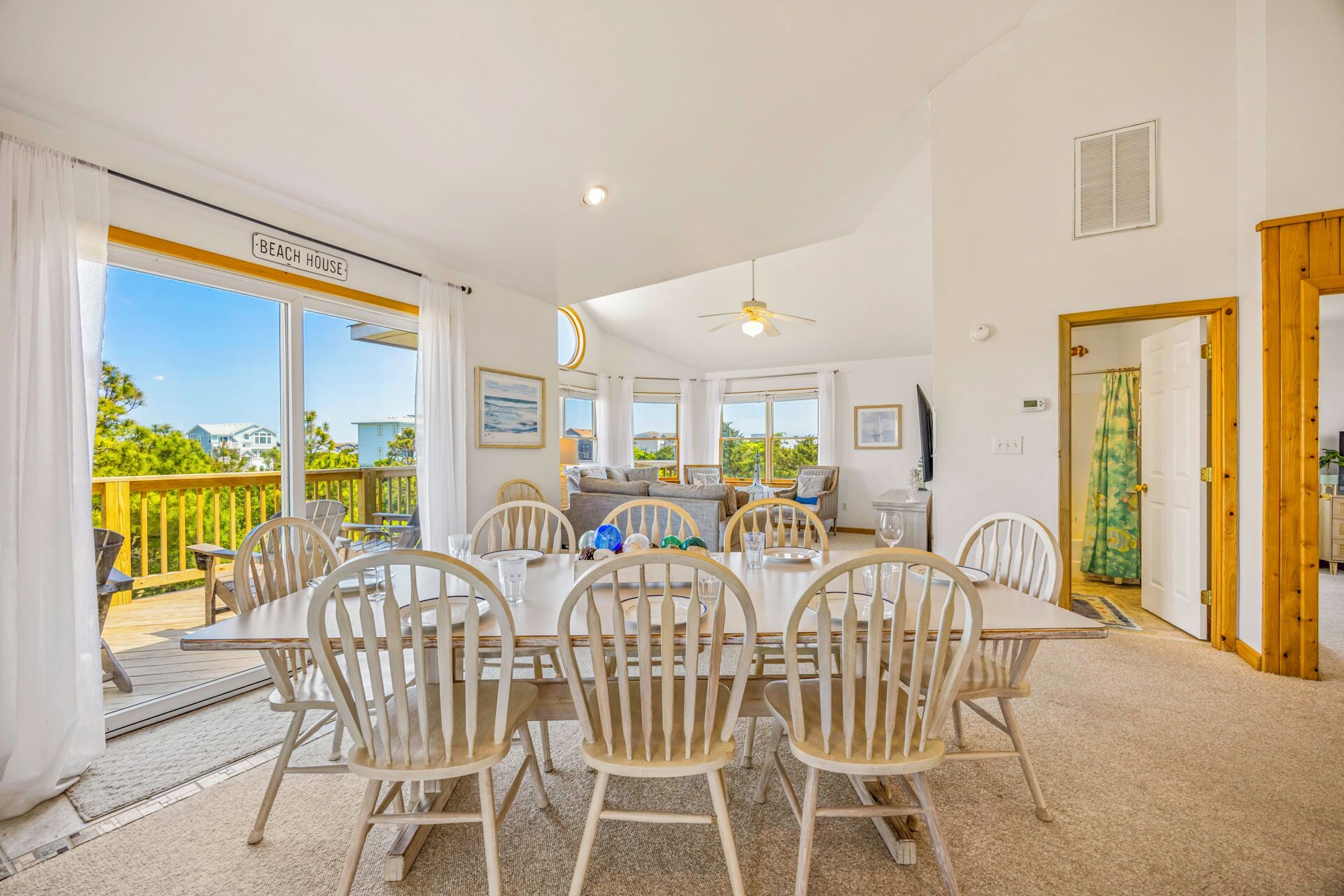 A dining area with a table and chairs, a ceiling fan, and a view of the outdoors.
