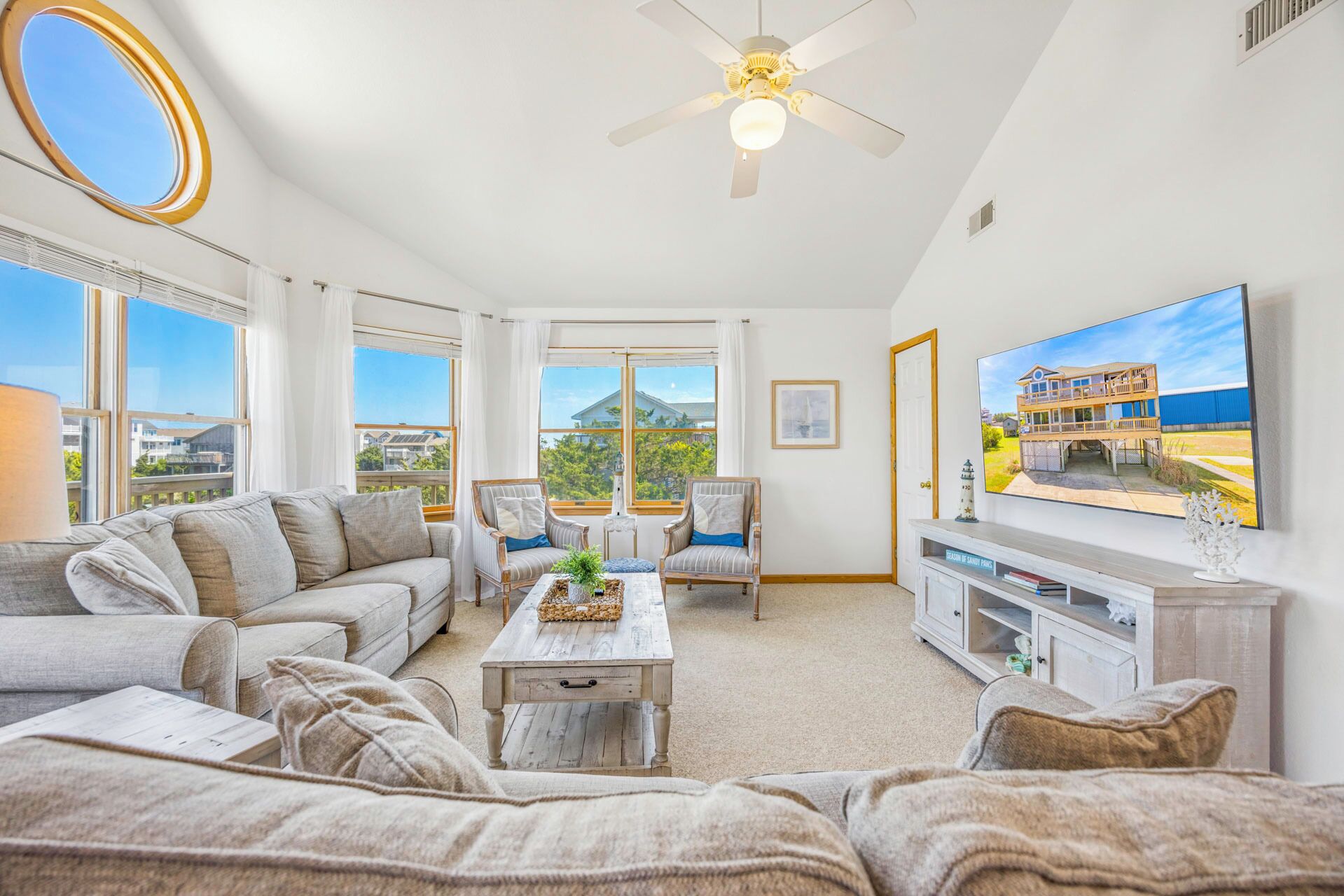 A living room with a sofa, armchairs, a coffee table, a TV, and a ceiling fan.