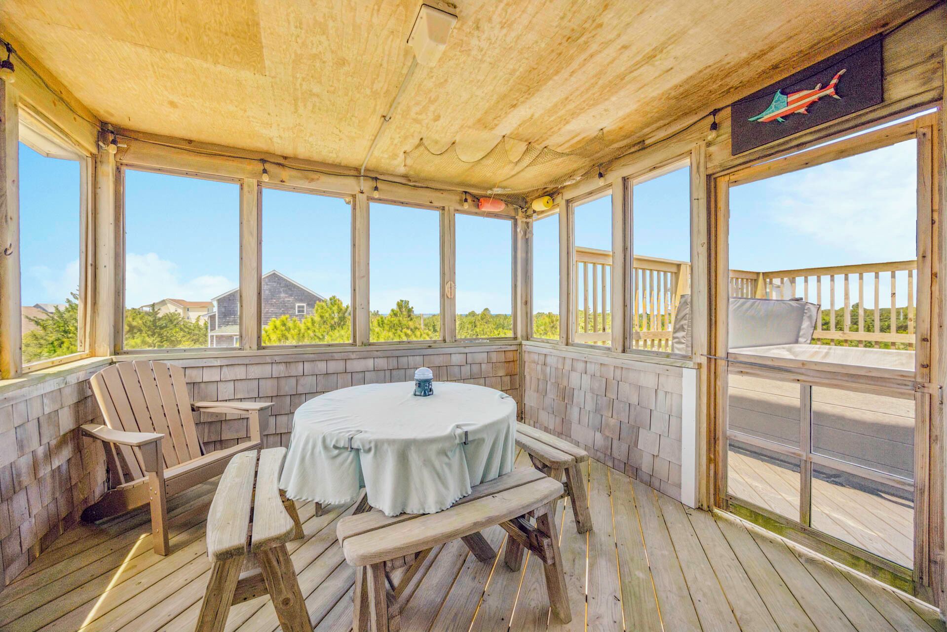 Un espace extérieur abrité, doté d’une table ronde et de bancs, de grandes fenêtres et offrant une vue sur le paysage environnant.