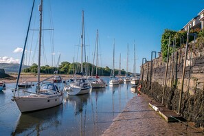 A marina with boats docked along a stone wall, calm water, and a clear sky. - Seaside Holiday Cottage Criccieth | Towyn (Criccieth)