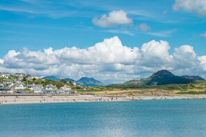 A coastal town with a beach, houses, and mountains in the background. - Seaside Holiday Cottage Criccieth | Towyn (Criccieth)