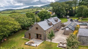 Une maison en pierre avec un toit en pente, une allée pavée et un petit jardin.