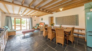 Une pièce spacieuse comprenant un coin repas, un banc, des meubles en osier, un sol carrelé et un plafond en bois.