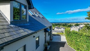 A residential building with a sloped roof, skylights, and a view of a green landscape. - Modern Four Bedroom Property with Sea Views | Tan-Y-Foel (Dyffryn Ardudwy)